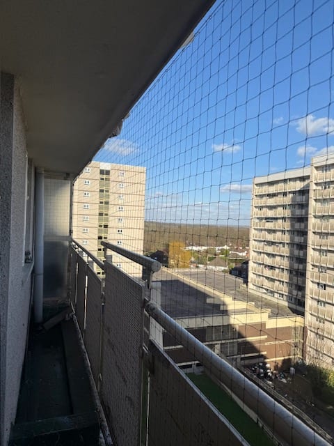 Bird netting to a residential walkway with tower blocks beyond