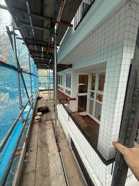Bird netting to a tiled facade above a swimming pool